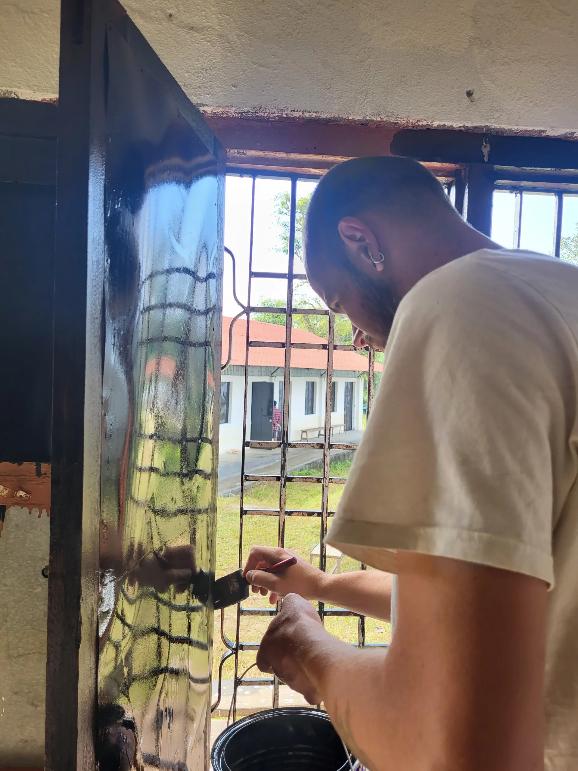 François repeint une porte métallique à l’intérieur de l’école.