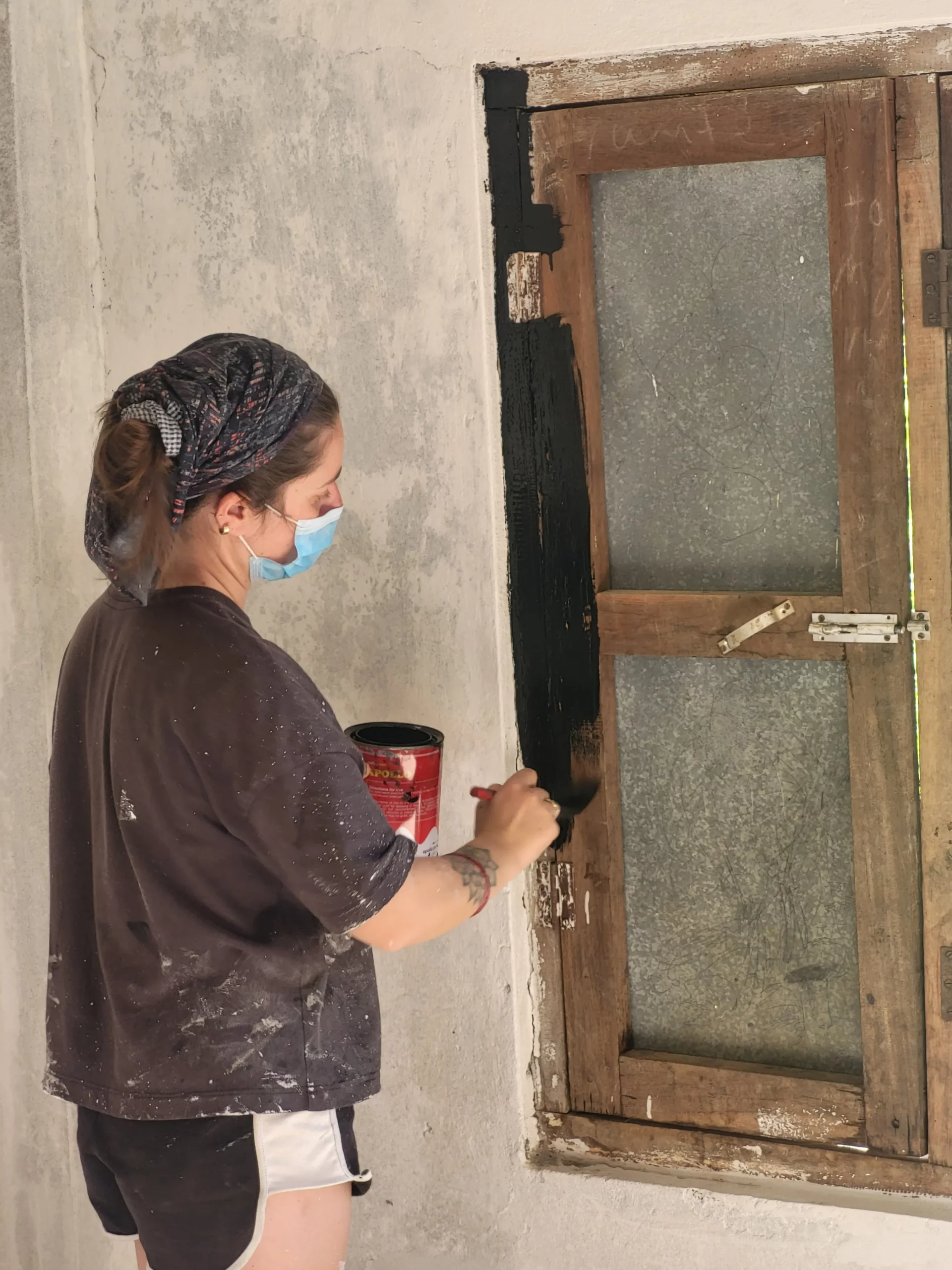 Mathilde repeint les encadrements de fenêtres.