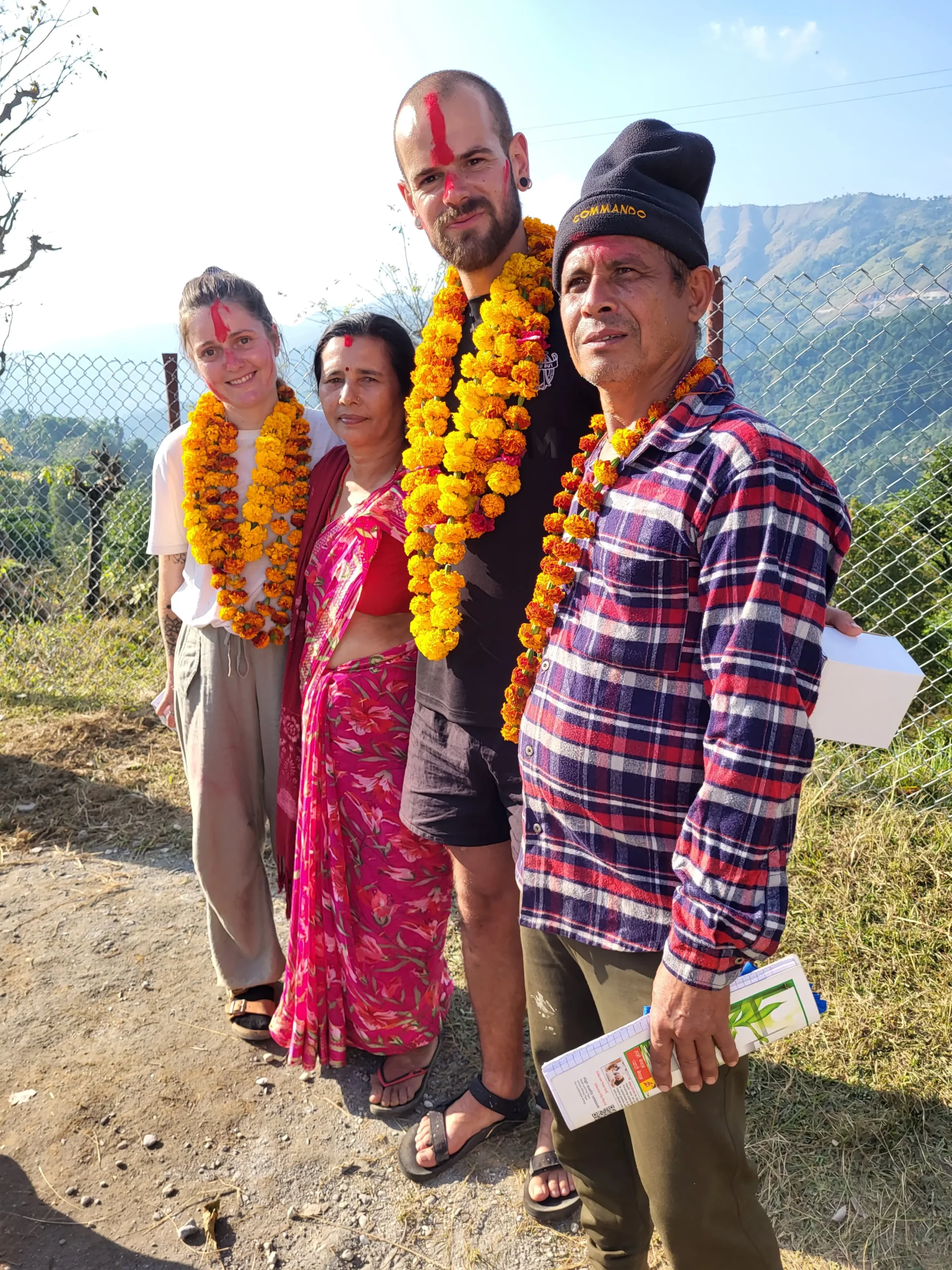Mathilde et François entourés d’habitants, colliers de fleurs autour du cou.