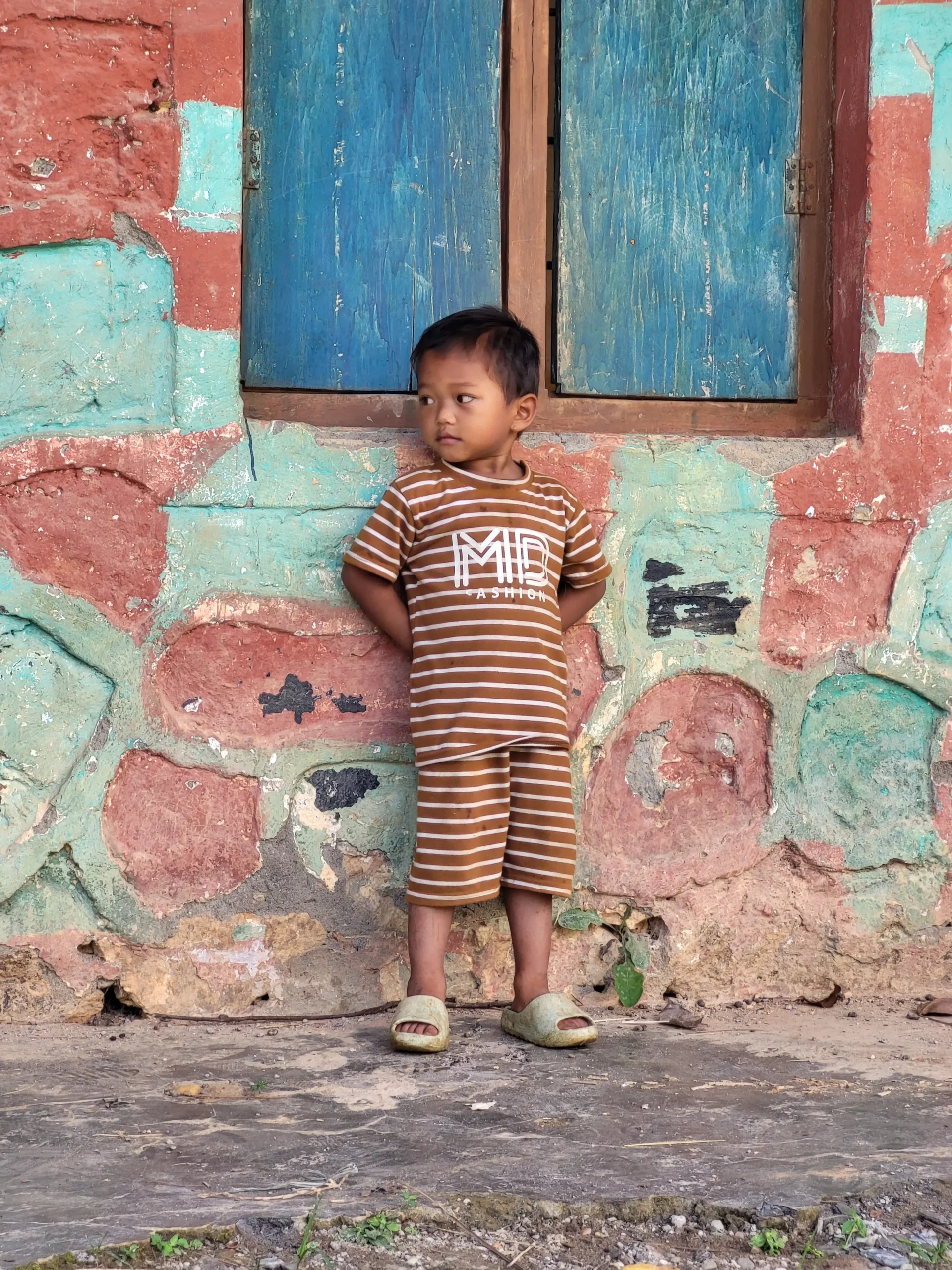 Jeune enfant appuyé contre un mur coloré.