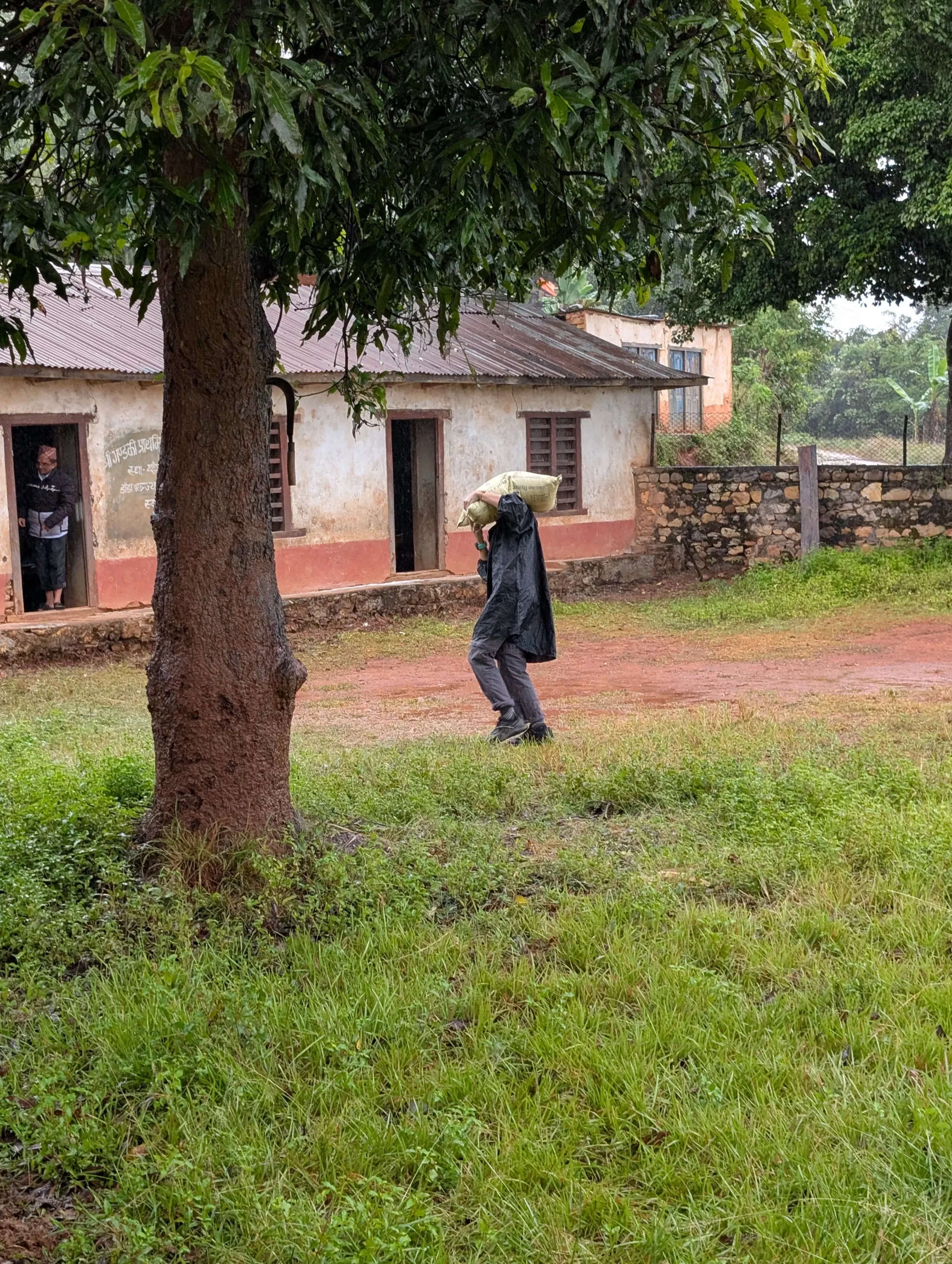 Habitant portant un sac de matériaux sous la pluie
