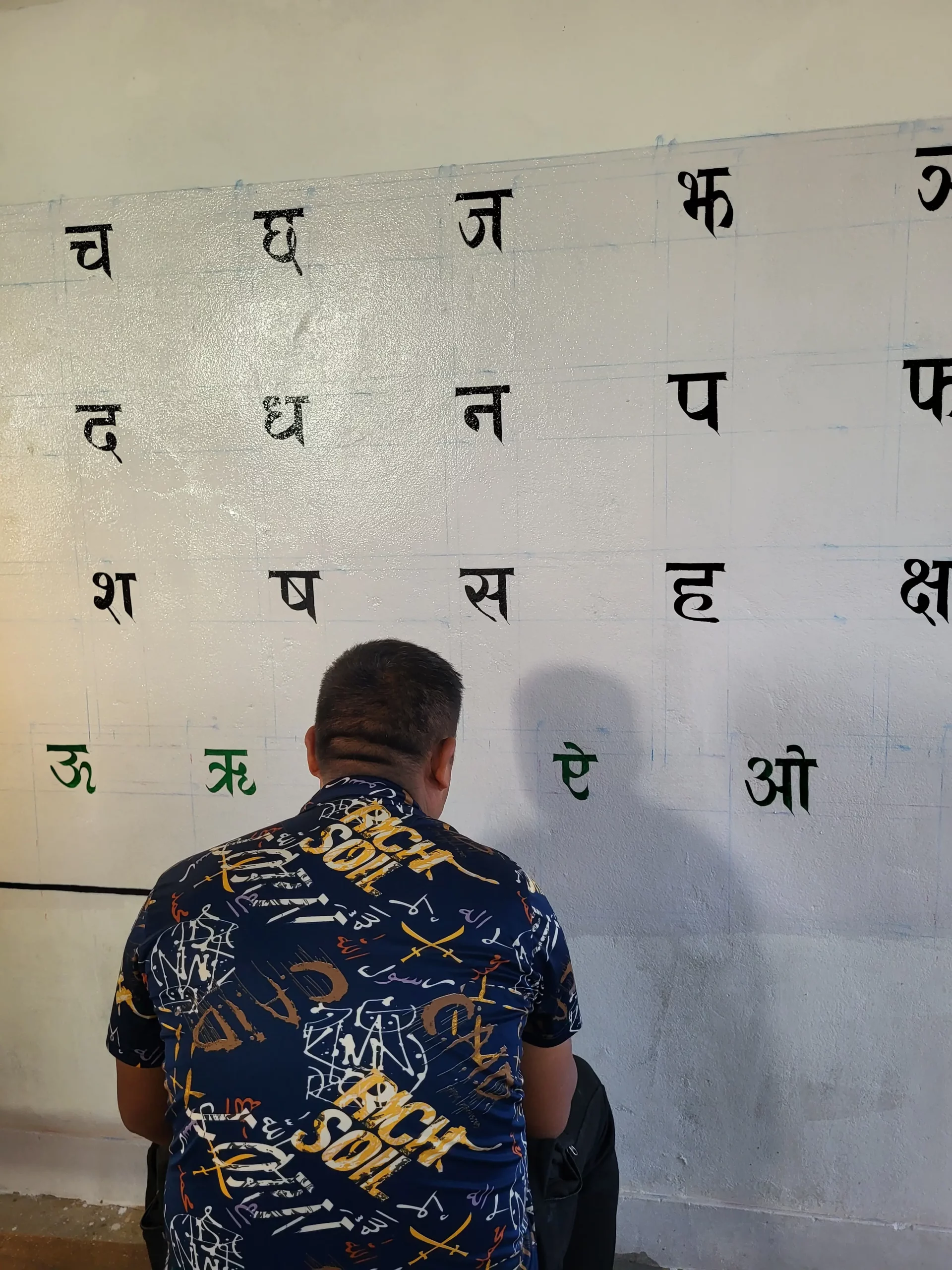 Artisan local réalisant des peintures pédagogiques sur un mur de classe.